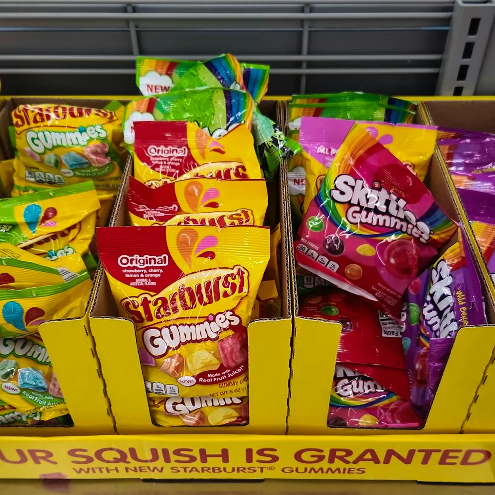 Bags of Starburst and Skittles gummies in a cardboard shop display
