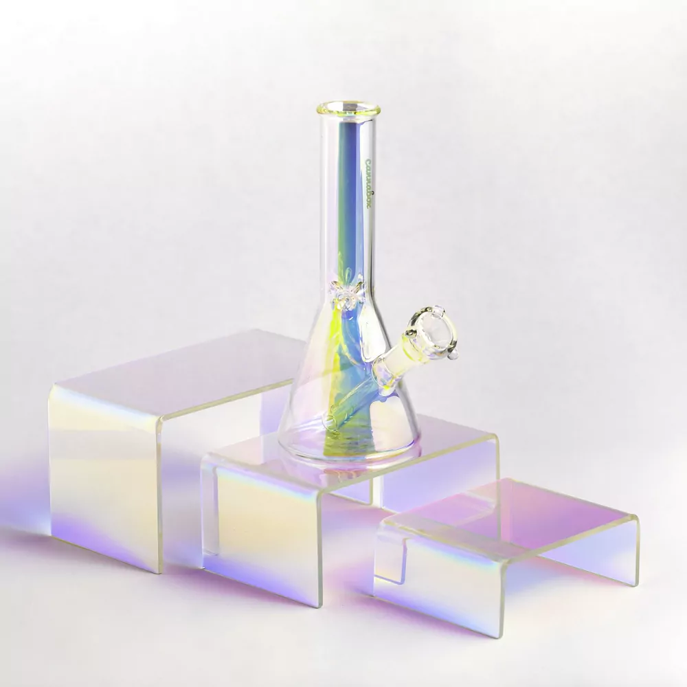 A clear beaker style glass water pipe with an iridescent stripe, on clear display risers