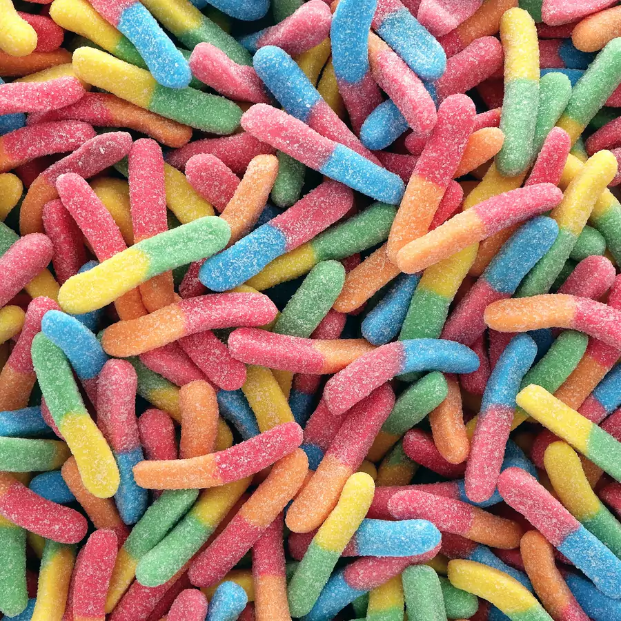 A pile of sugar coated sour gummy worms in bright colours
