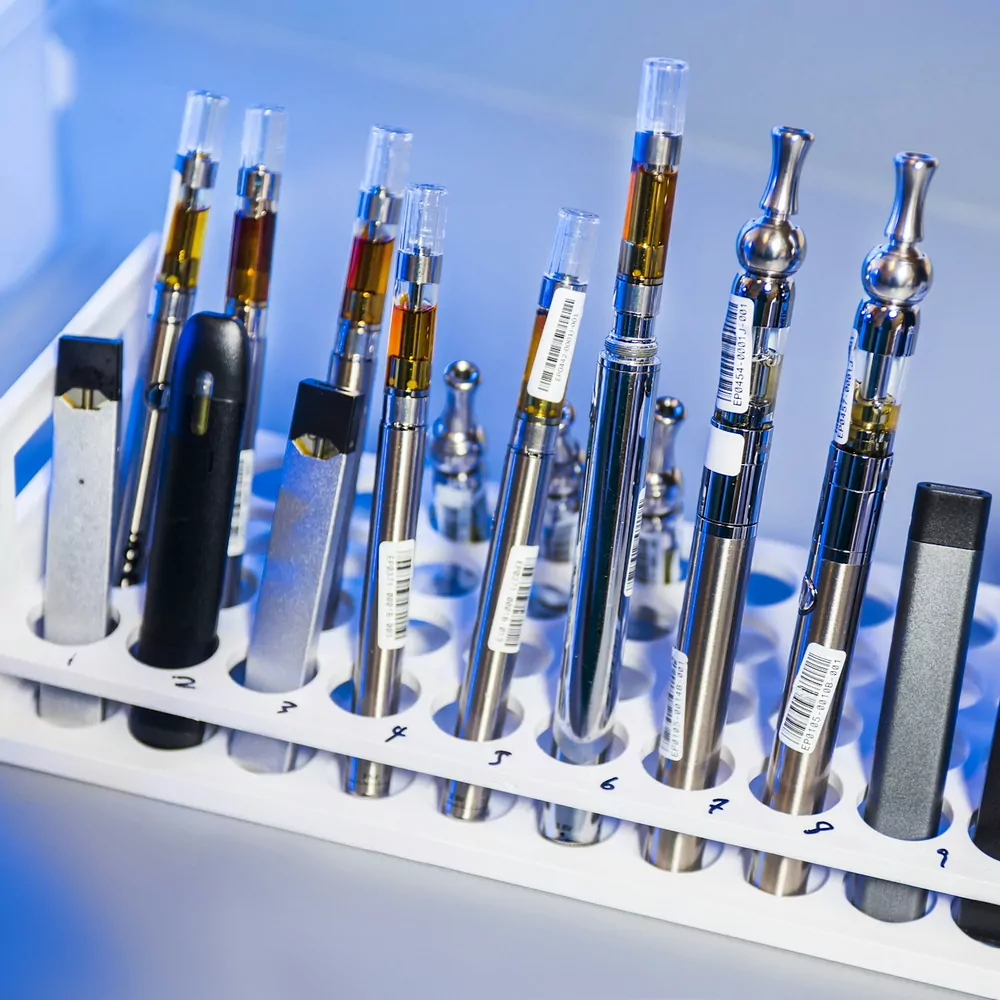 Vape pens, batteries and cartridges lined up in a white display stand