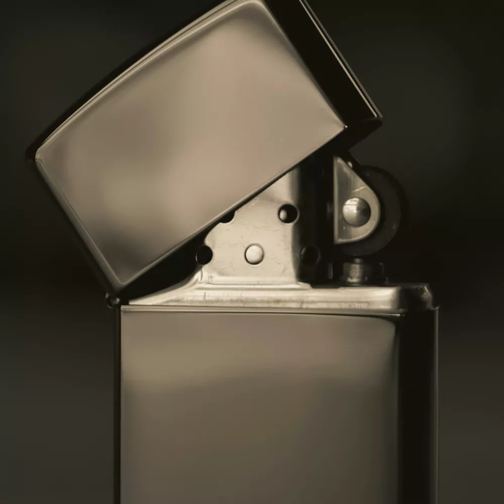 An open chrome Zippo style lighter on a dark background
